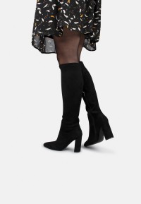 Model trägt schwarze Strumpfhose und Kleid, kombiniert mit Lauren Stiefeln von Posh by Poelman.