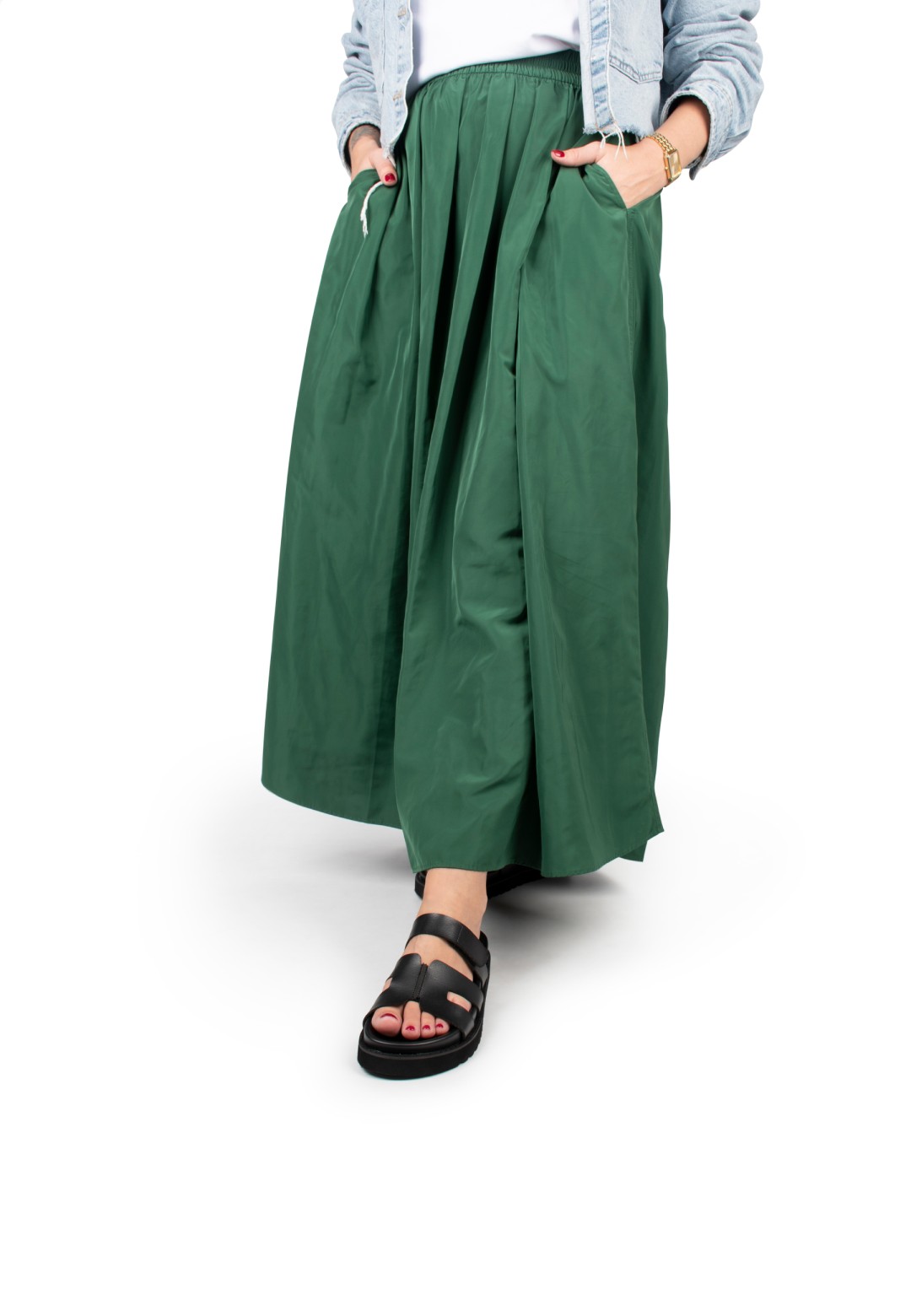 Close-up of model wearing a green skirt and black Scottie sandals made of faux leather.