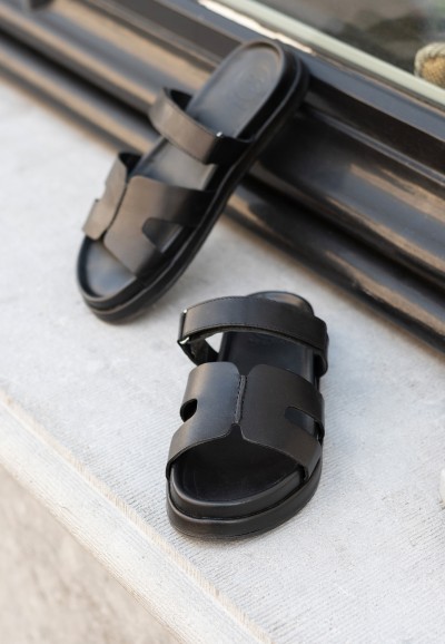 Close-up of the black Mag sandal – leather straps and flat sole.