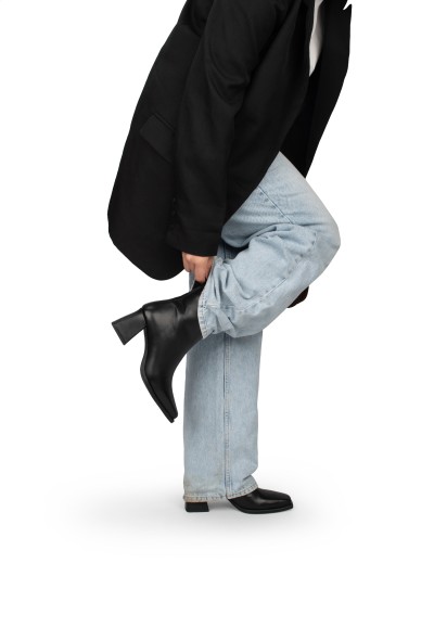 Model draagt blauwe jeans met zwarte leren Dua enkellaarzen van PS Poelman.