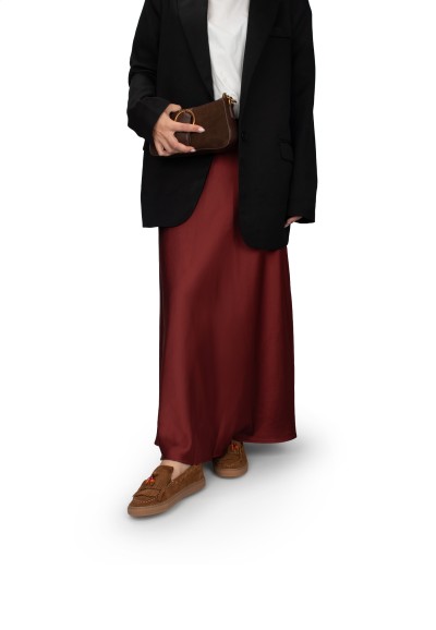 Vrouw draagt PS Poelman suède loafers met bordeauxrode rok en zwarte blazer