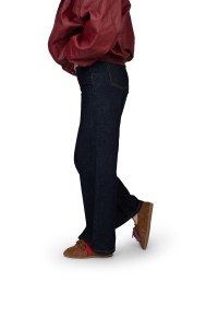 Zijaanzicht van model met donkerblauwe broek en bruine Vita loafers.