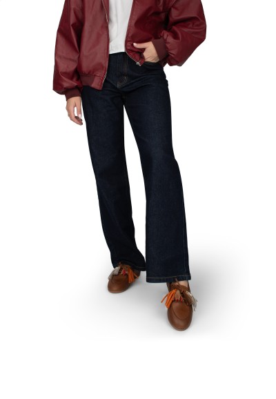 Model loopt met donkerbruine loafers en donkerblauwe jeans