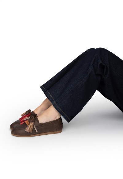 Model loopt met donkerbruine loafers en donkerblauwe jeans