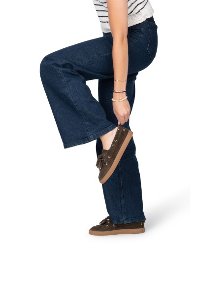 Model putting on dark brown loafers with jeans