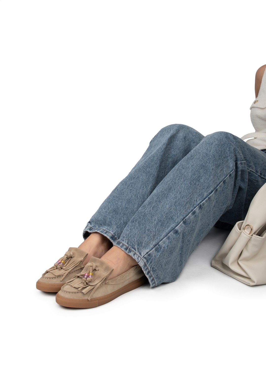Vrouw zit en draagt PS Poelman loafers met jeans