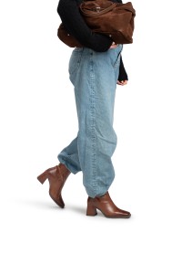Model trägt blaue Jeans mit cognacfarbenen Dua Stiefeletten von PS Poelman.