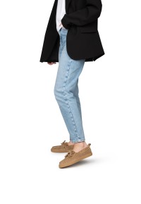 Vrouw met jeans en zwarte blazer draagt beige suède loafers – in beweging