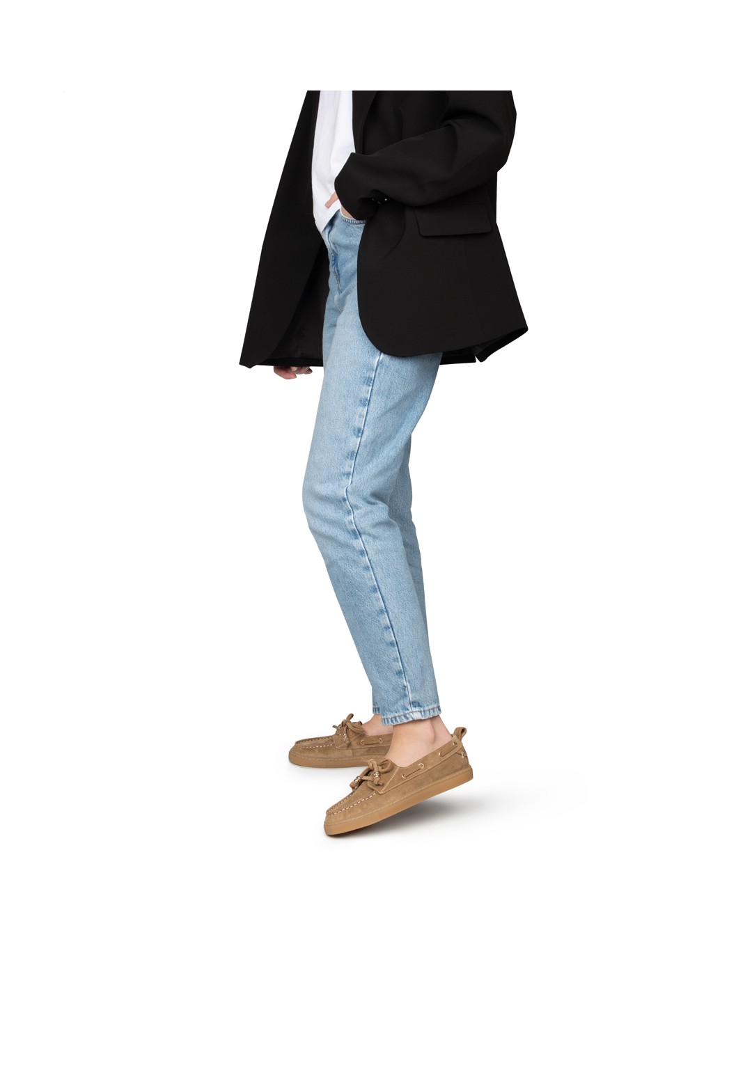 Vrouw met jeans en zwarte blazer draagt beige suède loafers – in beweging