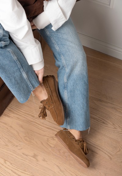 Close-up van LIRA loafers in camel suède – zittende vrouw met jeans