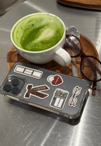 Handyhülle mit POELMAN.Brands Stickern, daneben Matcha-Latte und Brille