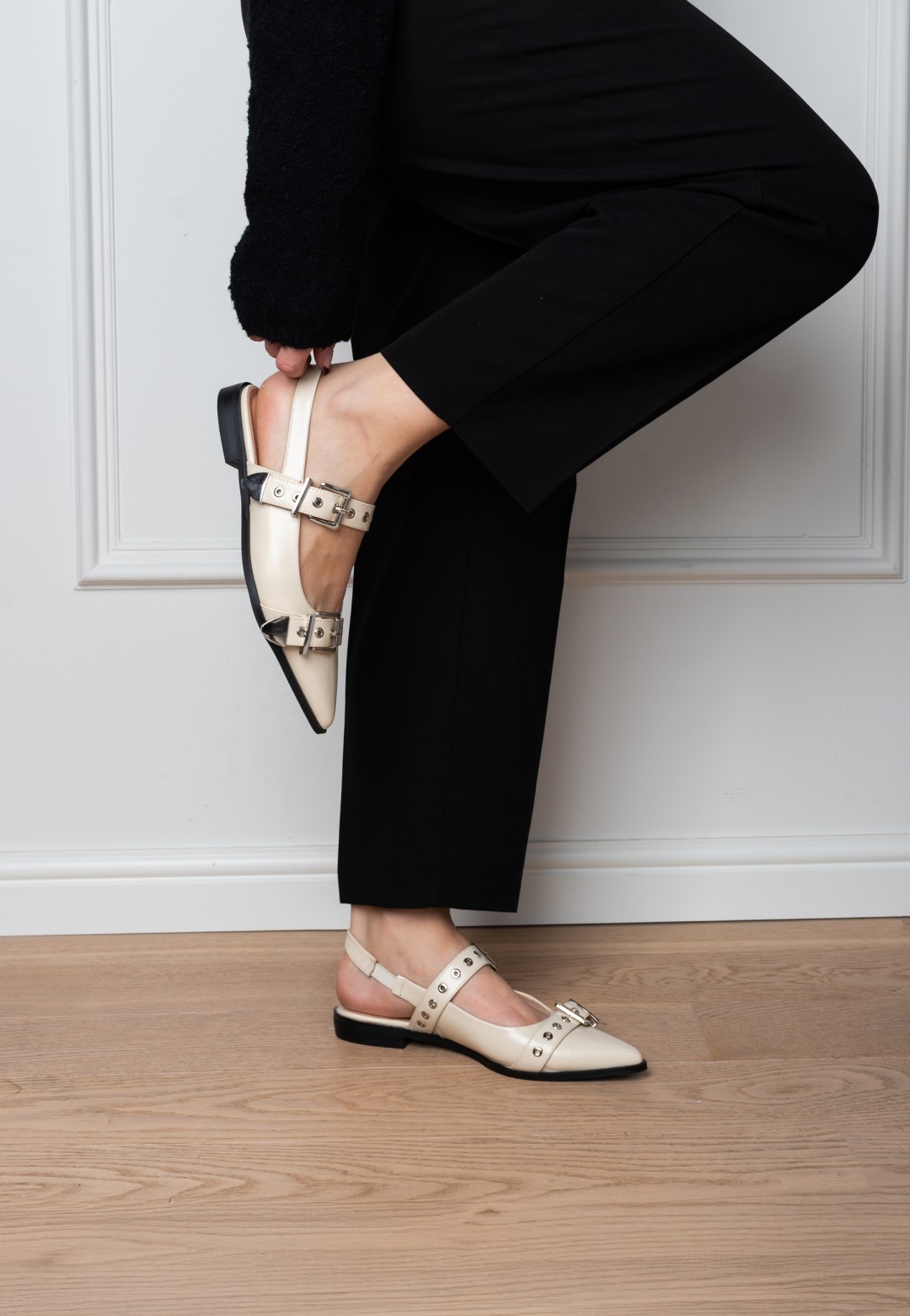 Close-up van JULIA slingbacks aan de voet bij witte muur