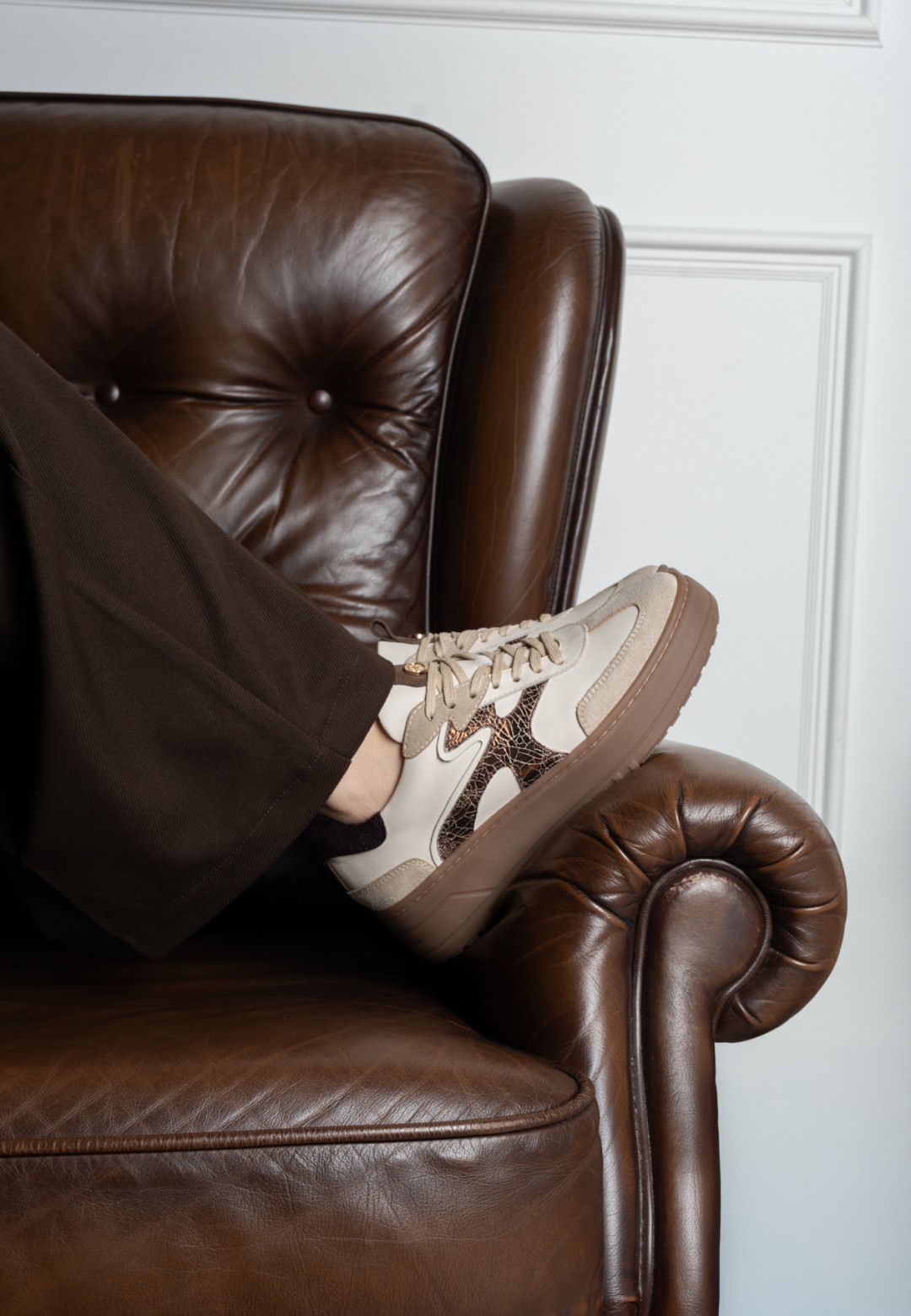 Model draagt Haboob Anemone beige sneakers zittend op stoel – lifestyle