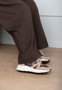 Close-up of the CAROCEL sneaker worn by model in brown trousers