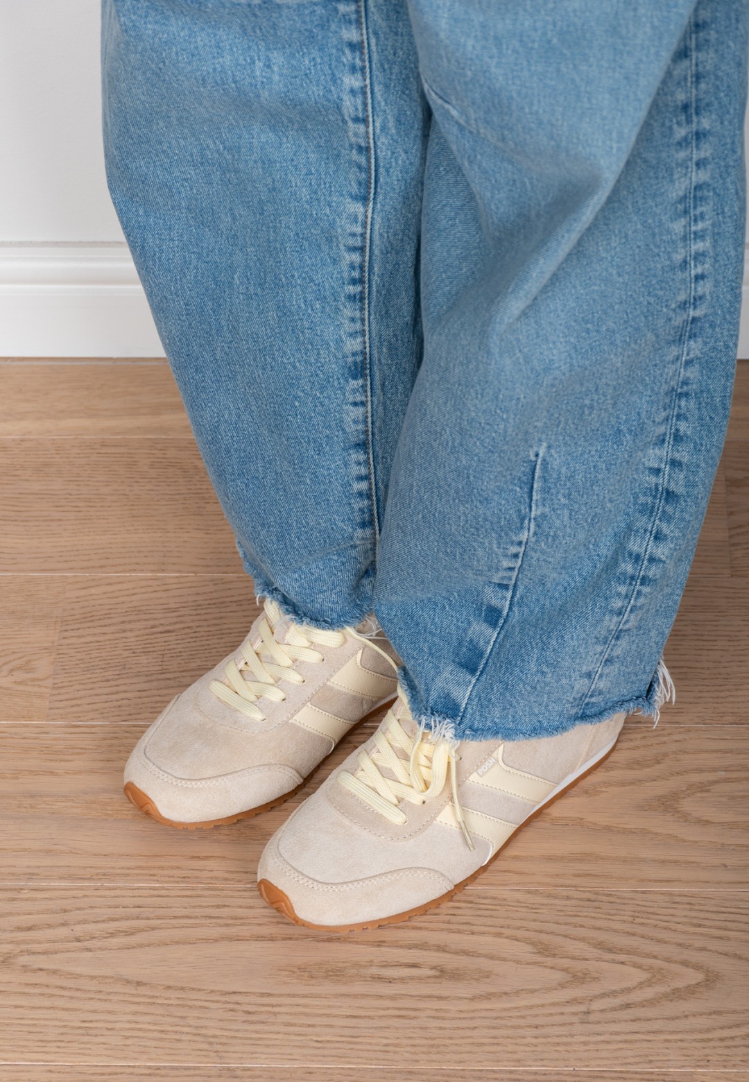 Model wearing the MAXINE sneaker by POSH by Poelman with wide leg jeans, side view