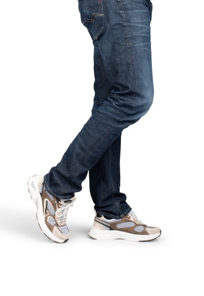 Model in Bewegung mit beigen Sneakern und dunkler Jeans