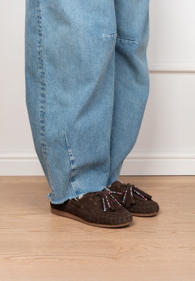 Bruine loafers met franjes gedragen, zijaanzicht op houten vloer