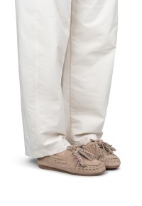 Model wearing beige suede loafers with fringe and bead detail