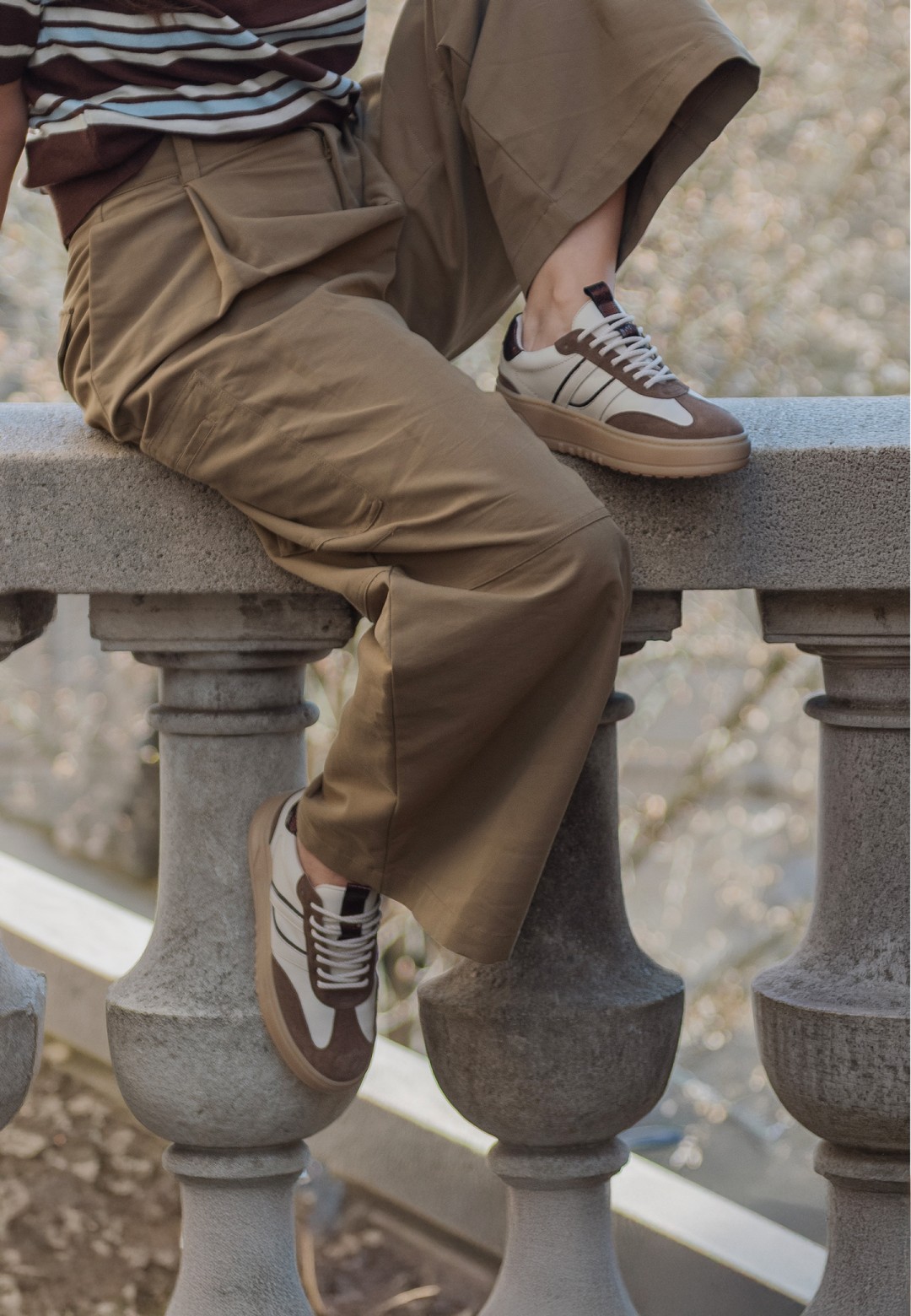 Model draagt de ANEMONE sneaker van POSH by Poelman onder een bruine broek