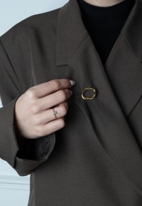 Model draagt gouden POSH by Poelman broche op blazer