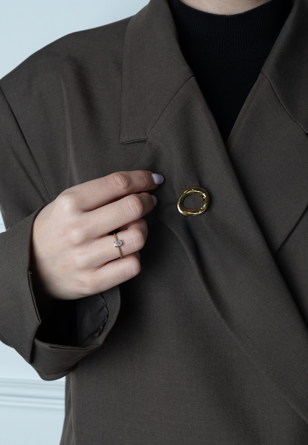 Model trägt goldfarbene POSH by Poelman Brosche am Blazer