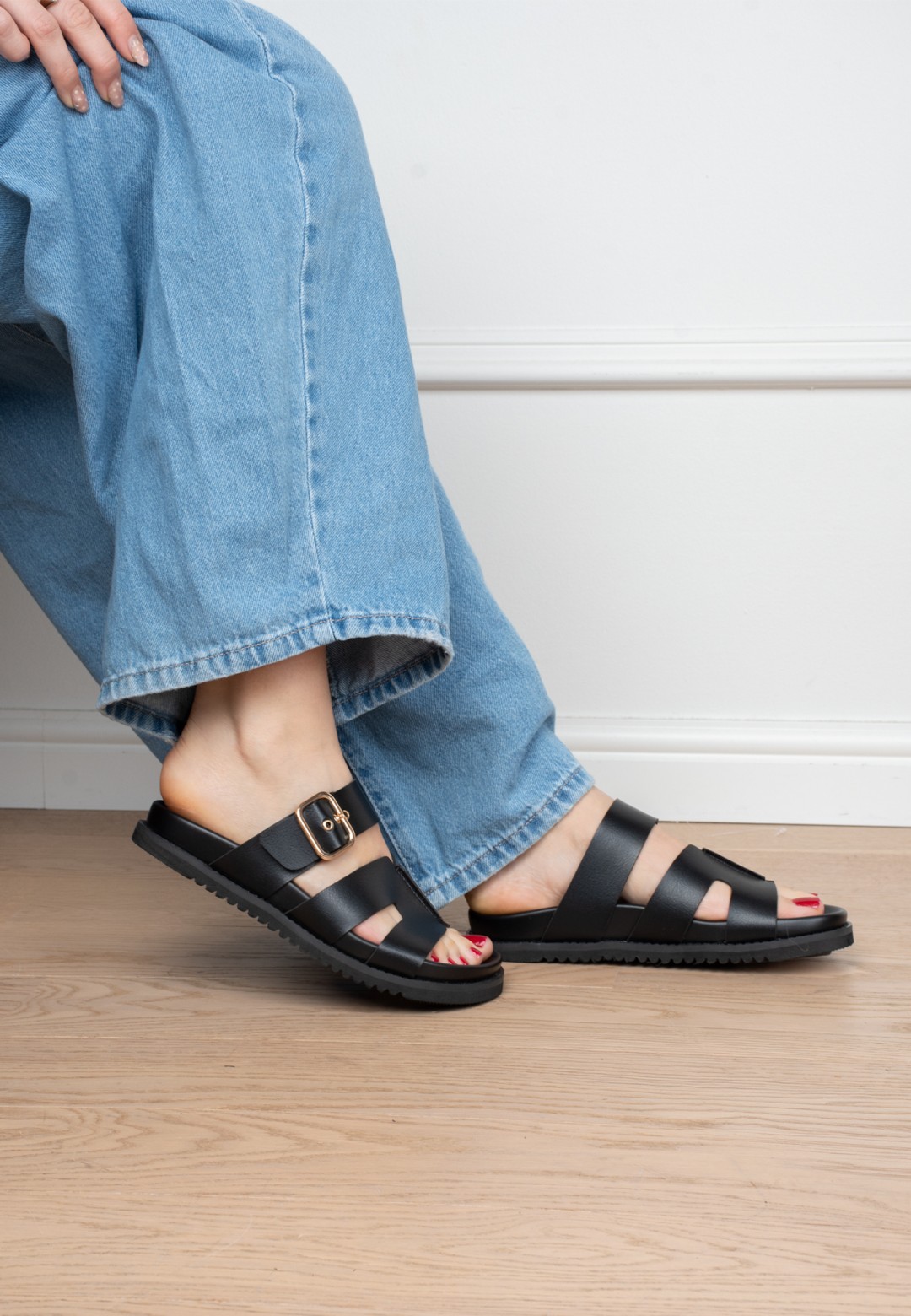 Model draagt POSH by Poelman Livia zwarte sandalen met denim jeans – indoor close-up