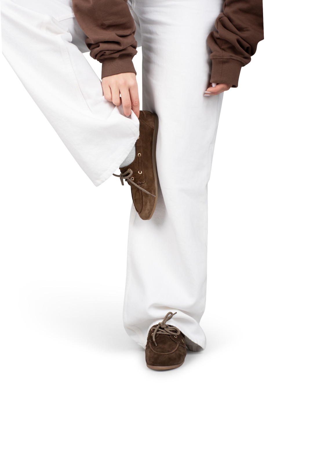 Brown suede loafers worn with white trousers, standing pose
