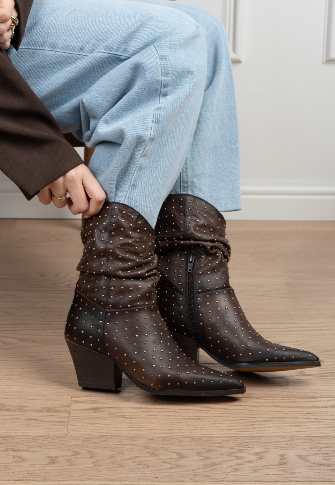 Model draagt PS Poelman Dali donkerbruine laarzen met studs en jeans – close-up