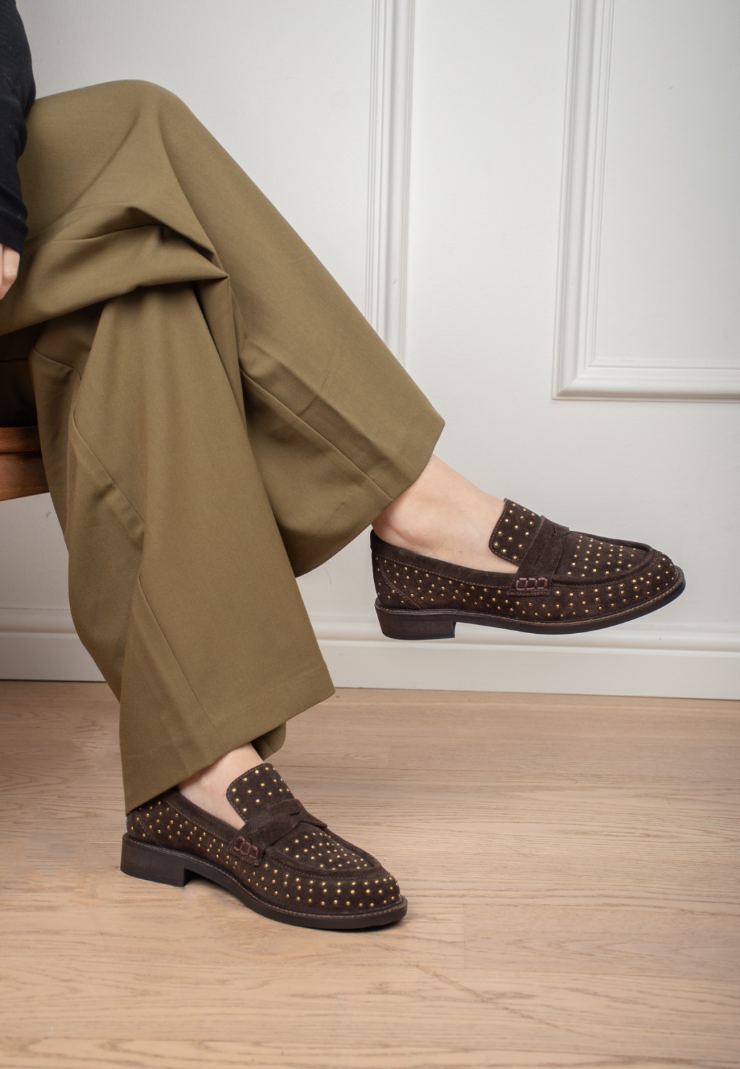 Model draagt Poelman Tika donkerbruine loafers zittend – close-up