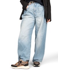 Model draagt POSH By Poelman Kiki zwart beige sneakers met wijde jeans – vooraanzicht
