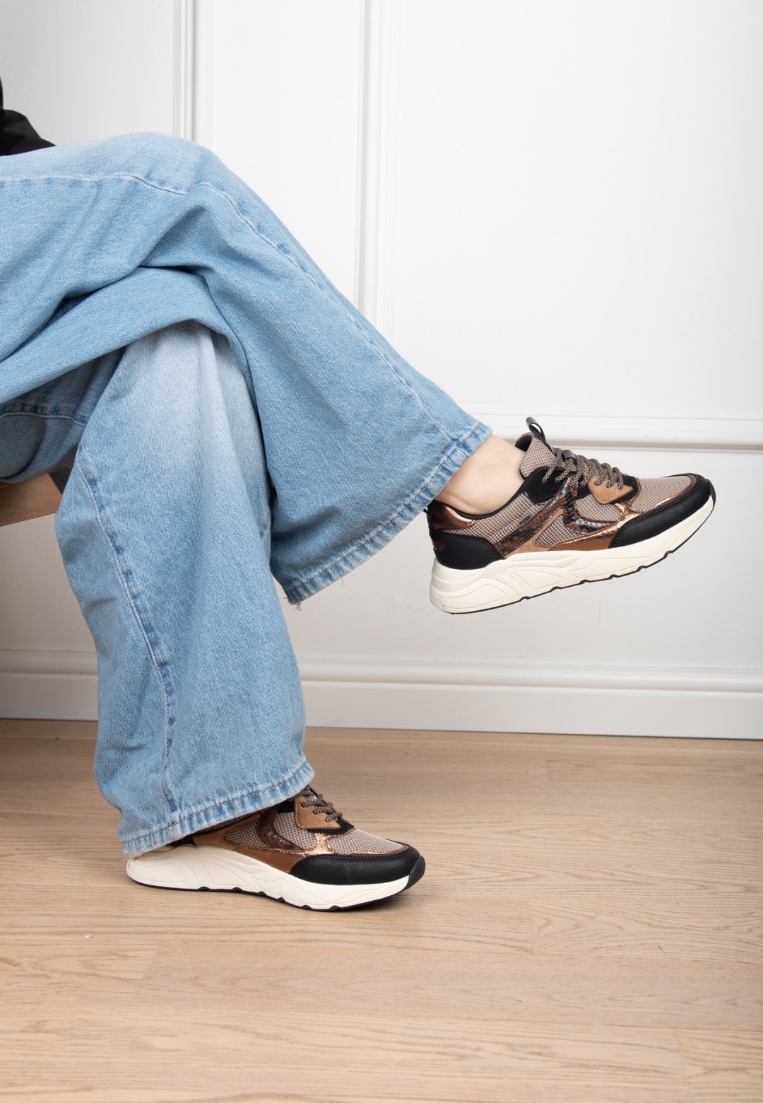 Model draagt POSH By Poelman Kiki zwart beige sneakers met lichte jeans – zittend detail