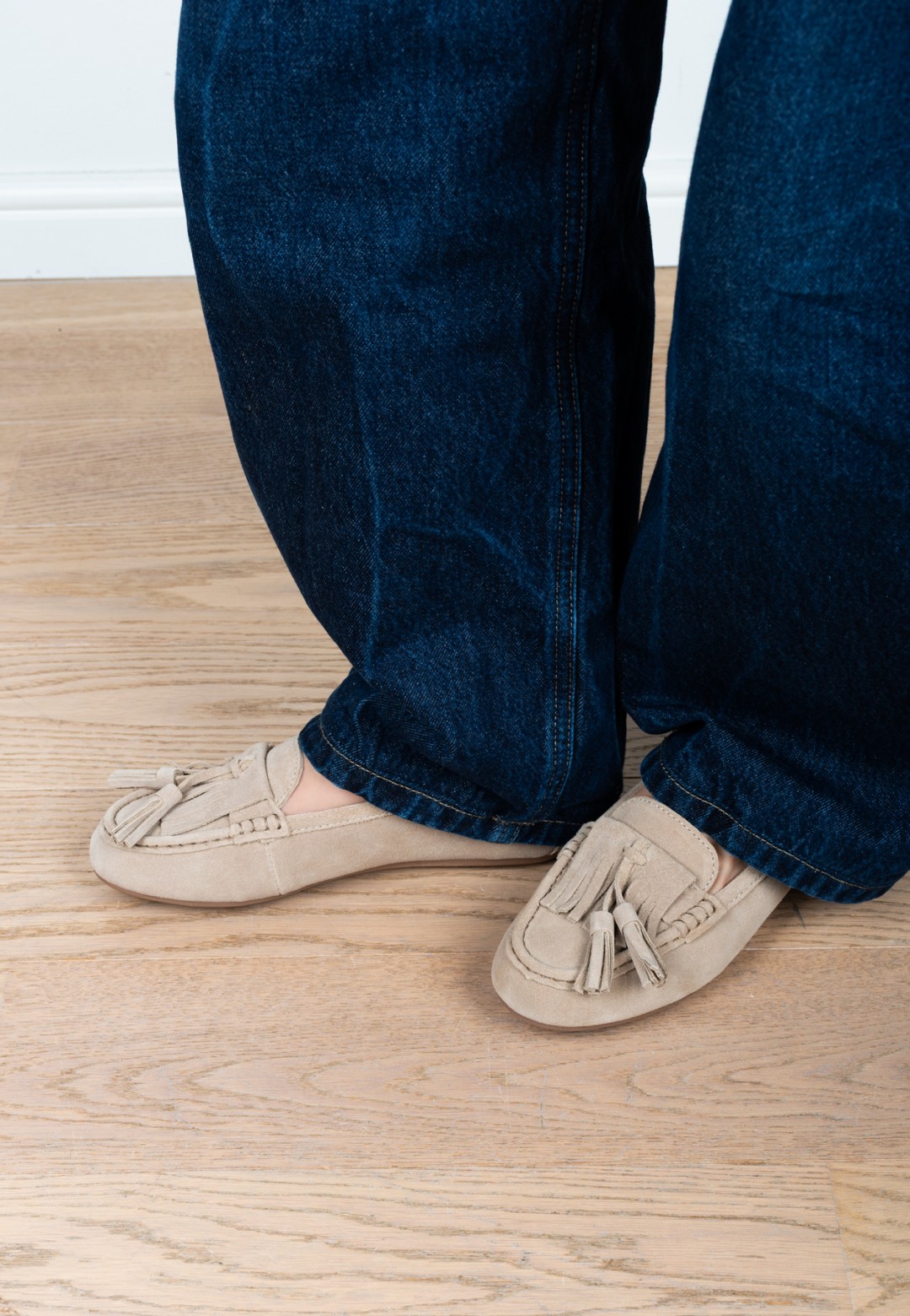 Model draagt PS Poelman Taya loafers in beige suède onder een donkere wide leg jeans