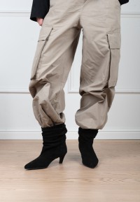 Model wearing the black suede Hannah boot by PS Poelman paired with beige trousers.