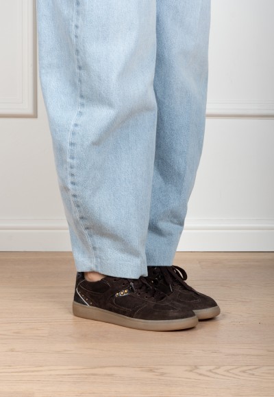 Model wearing dark brown Skye sneakers by PS Poelman paired with light blue jeans.