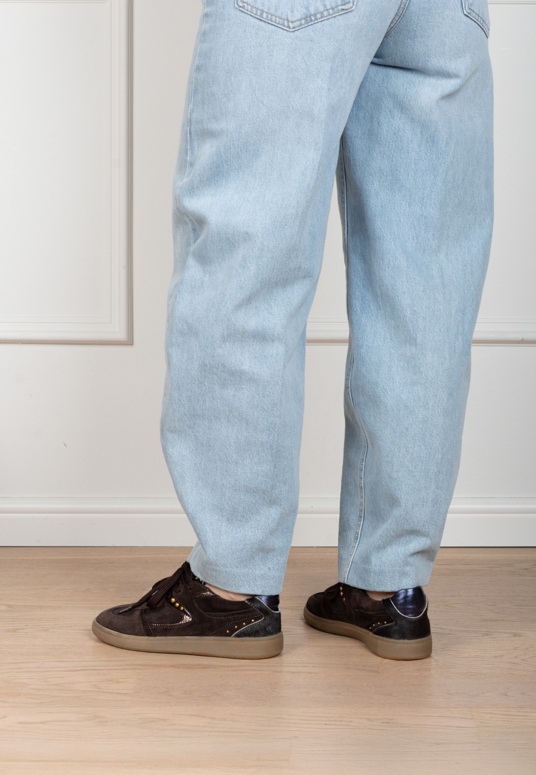 Model wearing dark brown Skye sneakers by PS Poelman with light blue jeans.