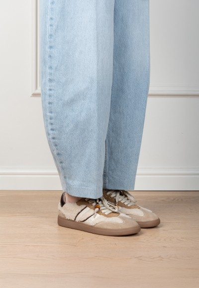 Model wearing HABOOB Skye beige sneakers with gold accents – front view