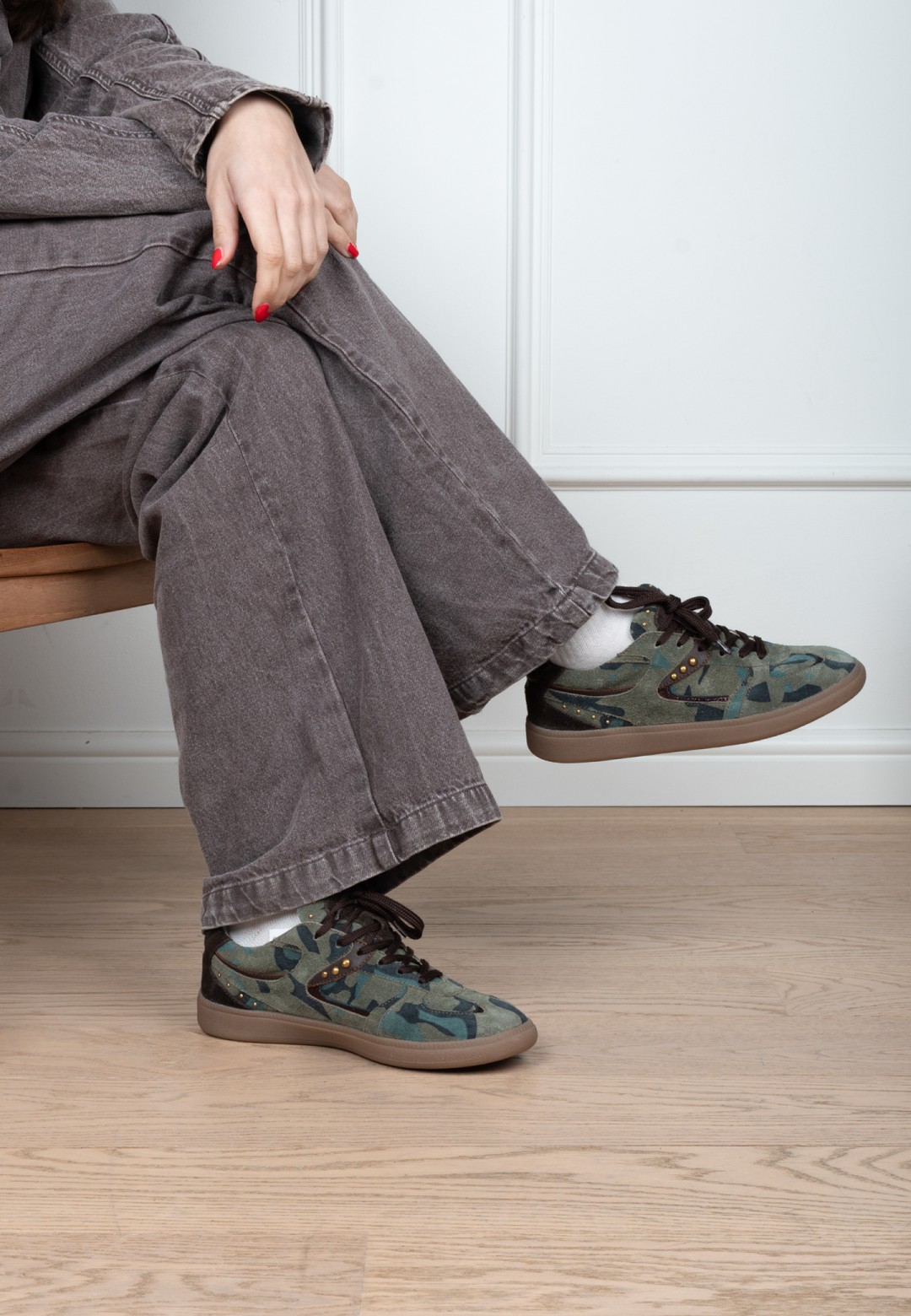 Model wearing Poelman Skye green camouflage sneakers – seated side view