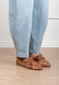 Side view of a model wearing cognac Poelman MIRA suede loafers with light blue jeans.