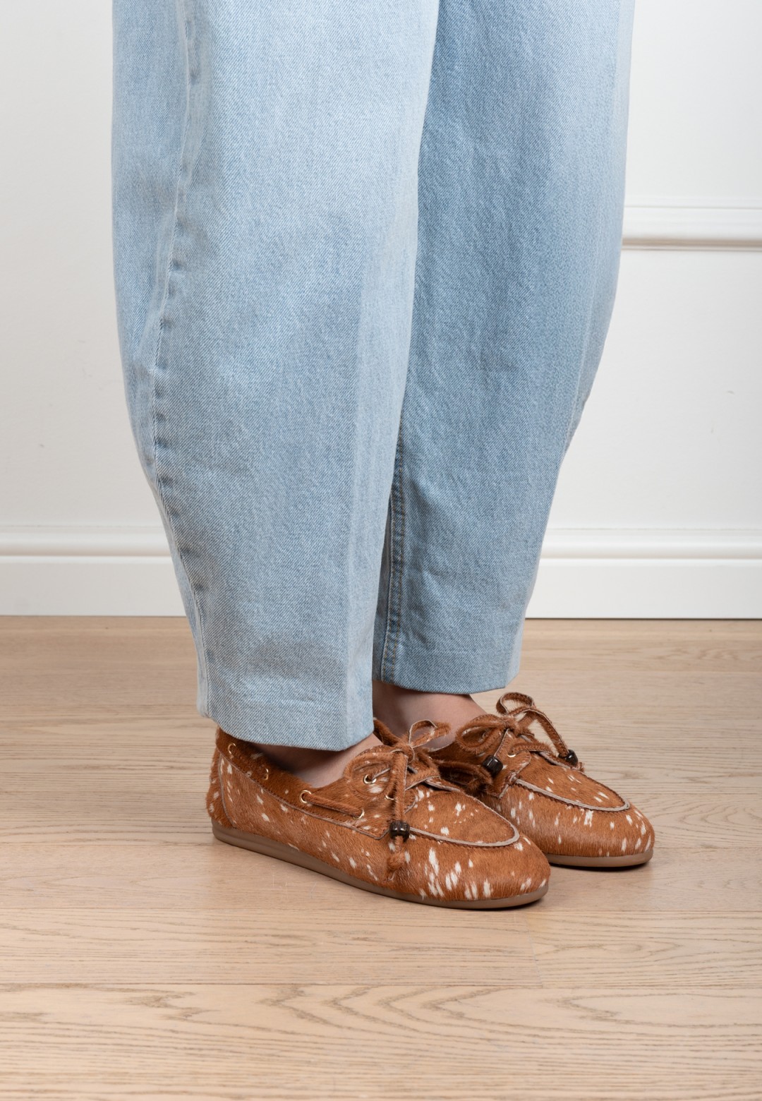 Seitenansicht eines Models mit cognacfarbenen Poelman MIRA Loafern aus Veloursleder und hellblauer Jeans.