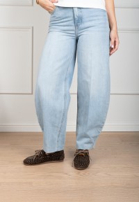 Model draagt Poelman Sira loafers in donkerbruin suède met studs, gecombineerd met een lichtblauwe jeans.