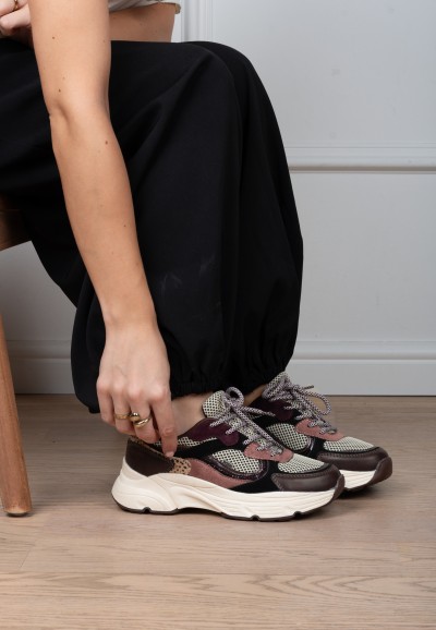 Model tying the laces of POSH By Poelman Angy burgundy animal print sneakers – close-up
