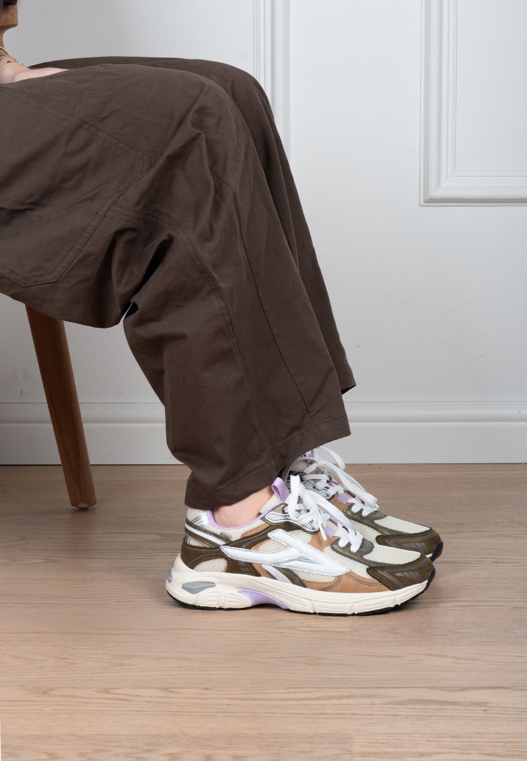 Model draagt POSH By Poelman Ginny wit-goud-lila sneakers met bruine broek – zijaanzicht