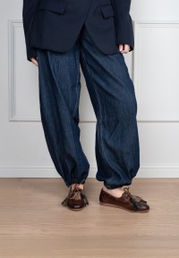 Model wearing Poelman Vita brown leather loafers with tassels and wide-leg jeans – front view