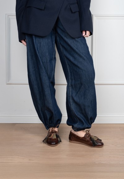 Model wearing Poelman Vita brown leather loafers with tassels and wide-leg jeans – front view