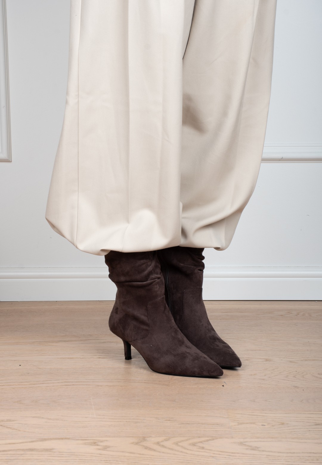 Model trägt POSH By Poelman Ellie dunkelbraune Stiefel mit heller Hose – Seitenansicht