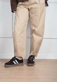 Model draagt POSH By Poelman Lilly donkerbruine sneakers met beige pantalon – staand