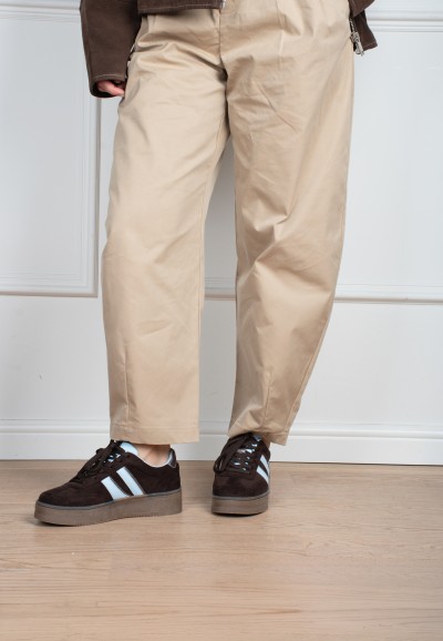 Model draagt POSH By Poelman Lilly donkerbruine sneakers met beige pantalon – staand