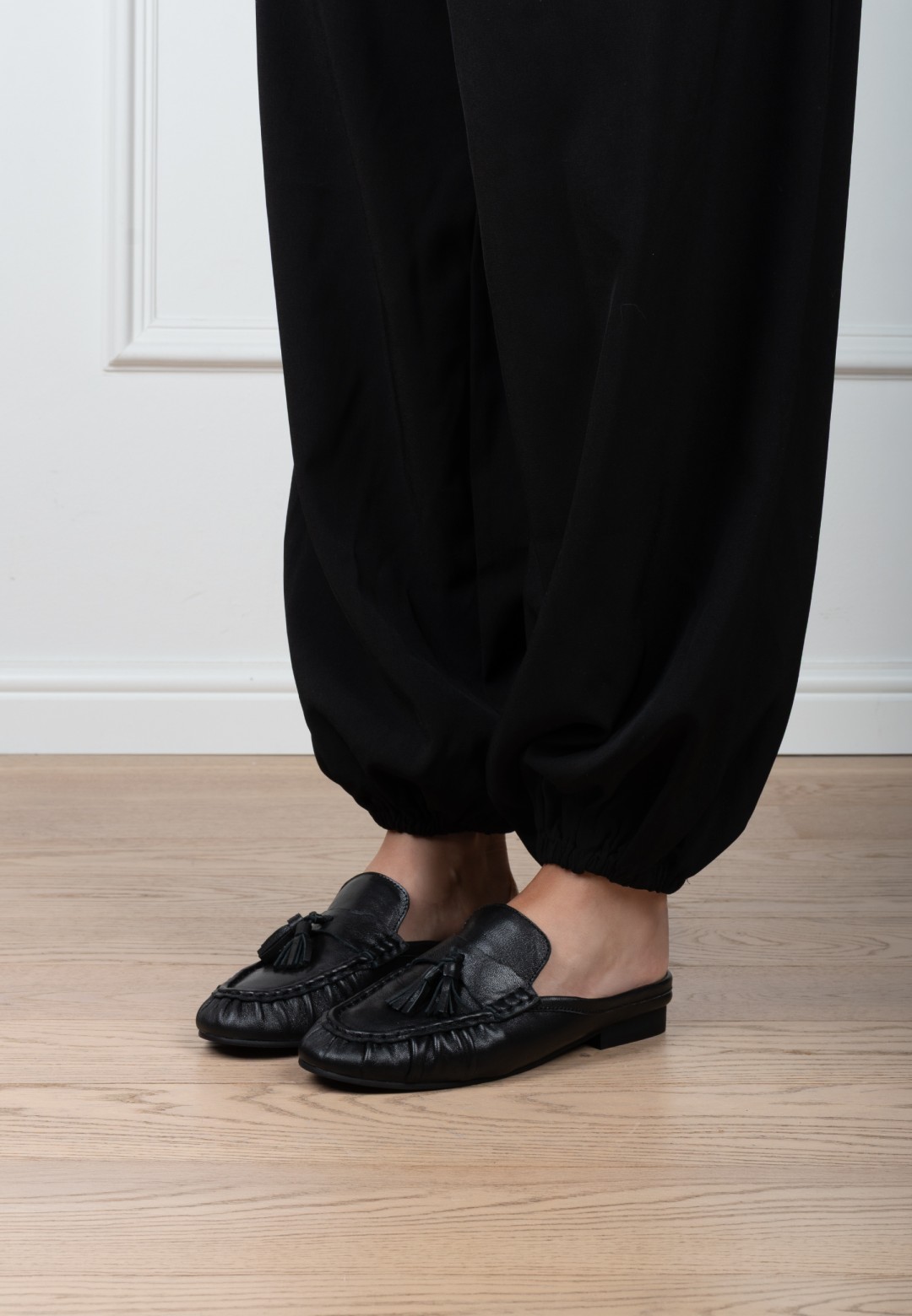 Poelman LOTTIE dames loafers van zwart leer gedragen onder een zwarte broek