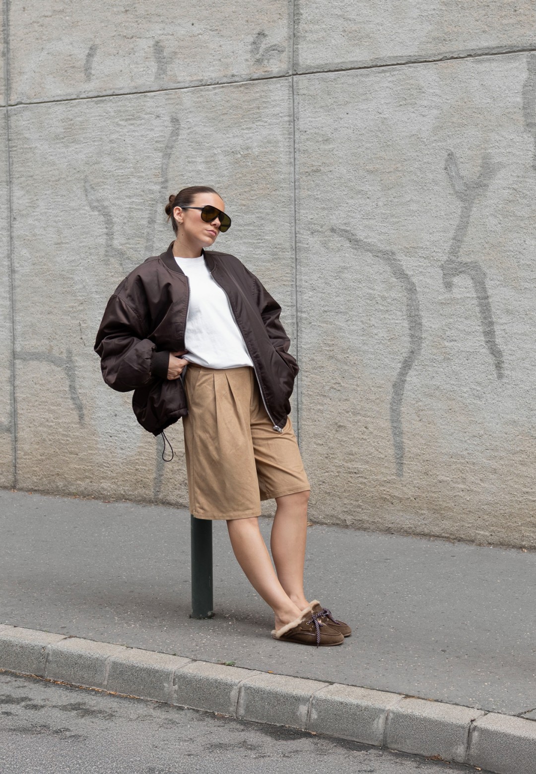 ISA bruine loafers gedragen met een beige pantalon en zwarte jas